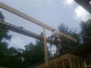 Carpenter setting a ridge beam over a new addition frame — Ice Dam Removal by Roofing Brothers in Woolwine