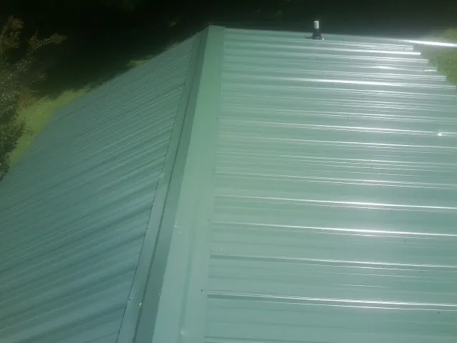 New green metal panels meeting at the ridge of a roof — Flat Roof Repair work by our crew in Woolwine