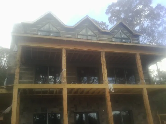 Dormers and porch framing on a large log home under construction — Roof Coating work by our crew in Woolwine