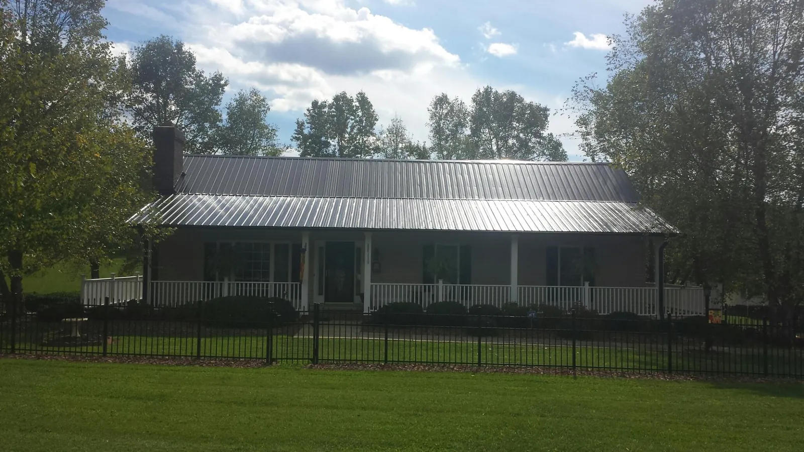 Gray metal roof on a brick ranch with a full width front porch — Gutter Guard Installation work by our crew in Woolwine