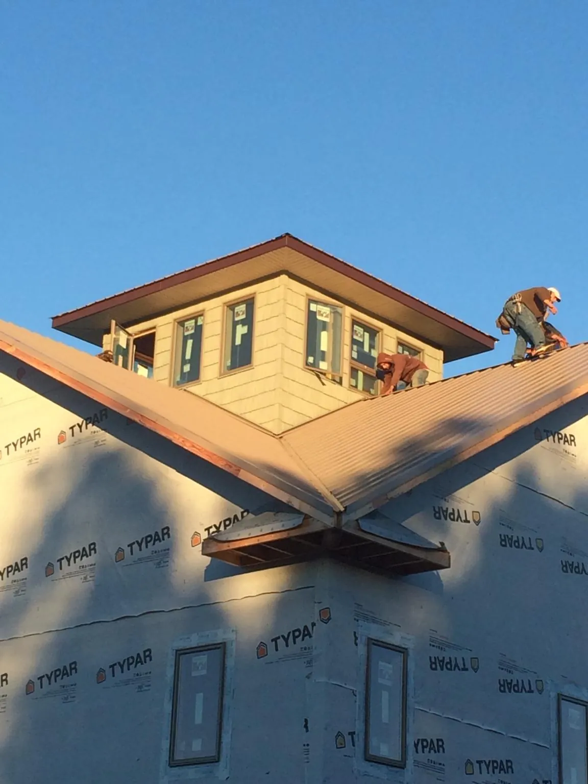 Roofers working around a rooftop cupola on a new metal roof at sunset — Roof Waterproofing in Woolwine by Roofing Brothers